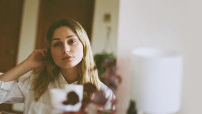 Woman looking into the camera with a potted plant blurred out in the foreground